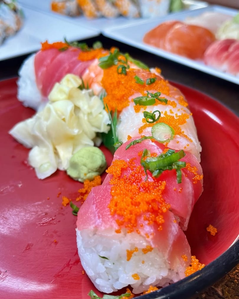 Colorful sushi roll with tuna, shrimp, roe, and scallions, served with ginger and wasabi.